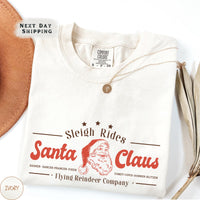 a santa claus t - shirt with a hat next to it