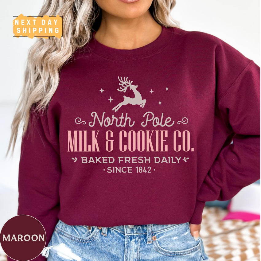 a woman wearing a maroon north pole milk and cookie co sweatshirt